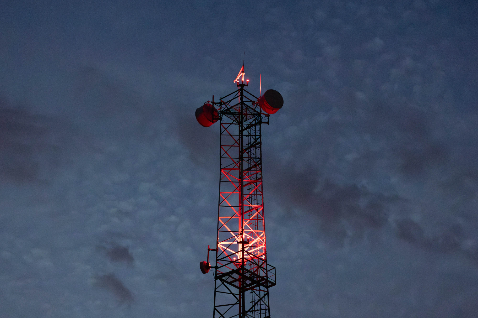 Torre de telecomunicaciones iluminada al anochecer